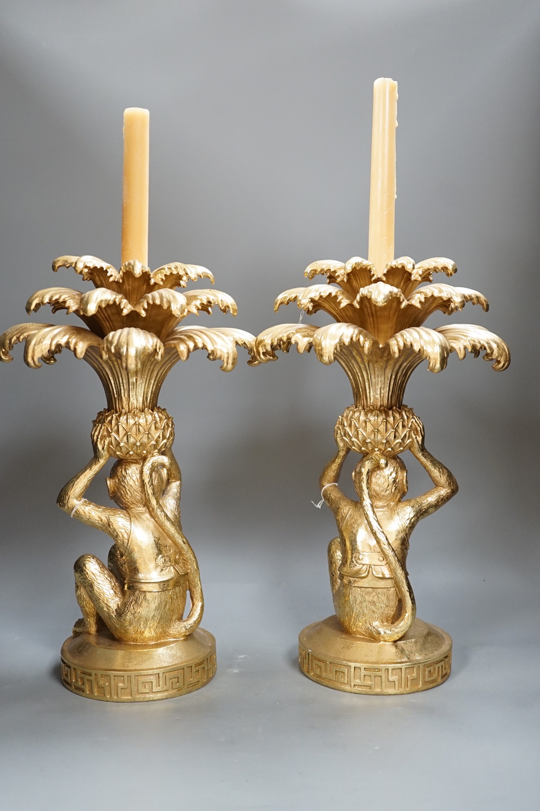 A pair of gilt resin ‘monkey and pineapple’ candlesticks. 37cm tall